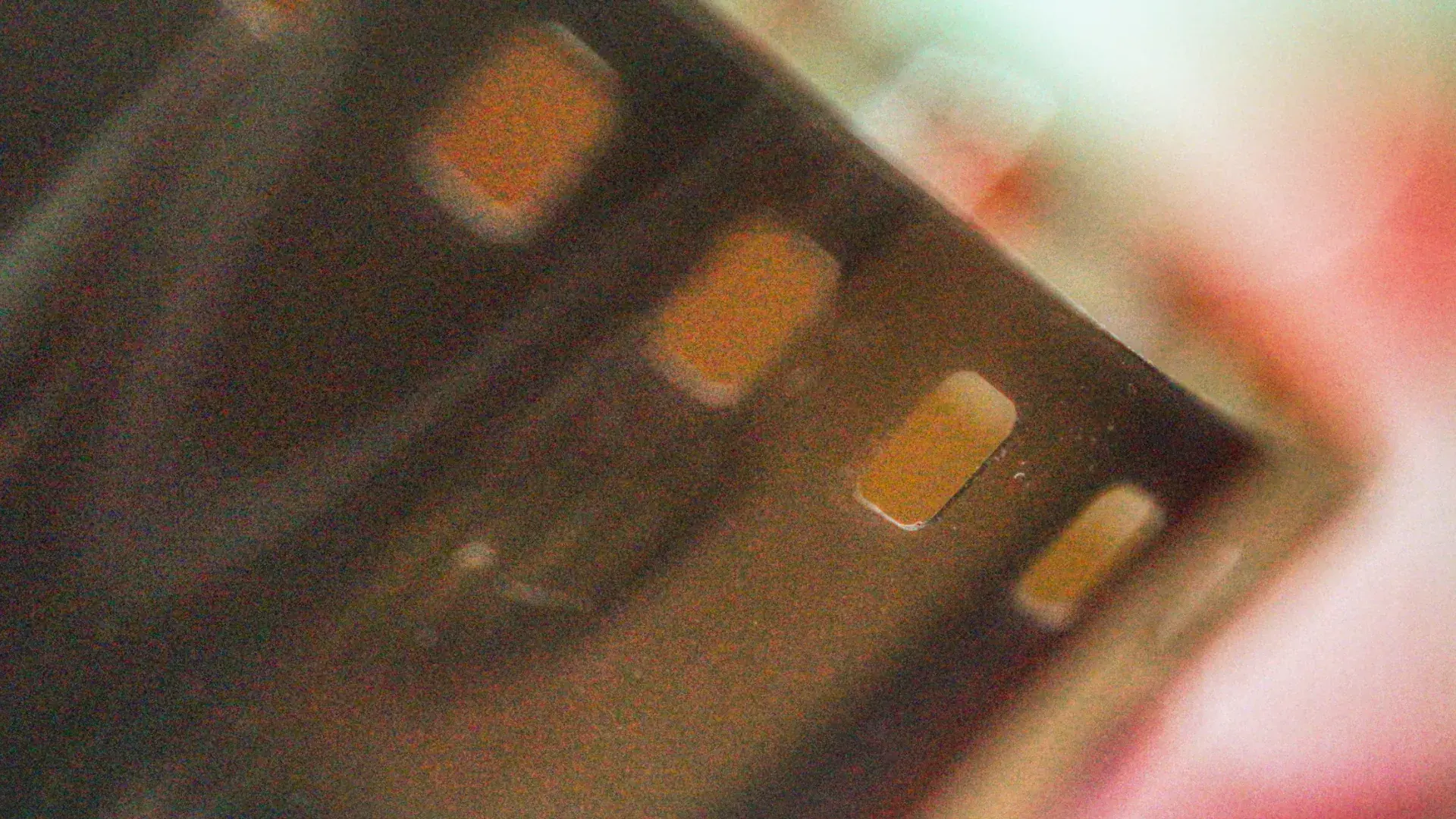 A grainy close-up of a dark film strip, its frames glowing amber in warm rose light: the Comptoir Café & Wine backdrop
