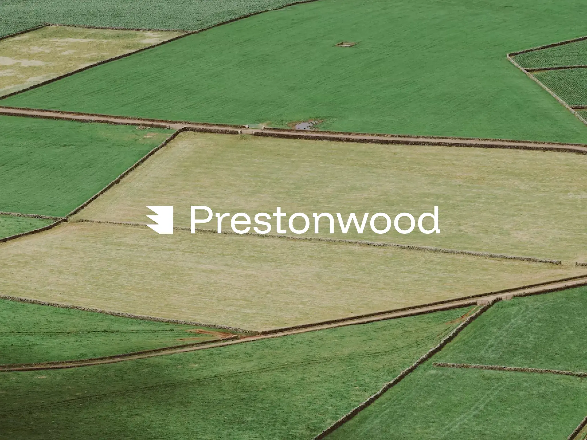 The Prestonwood logo in white over an aerial view of green fields